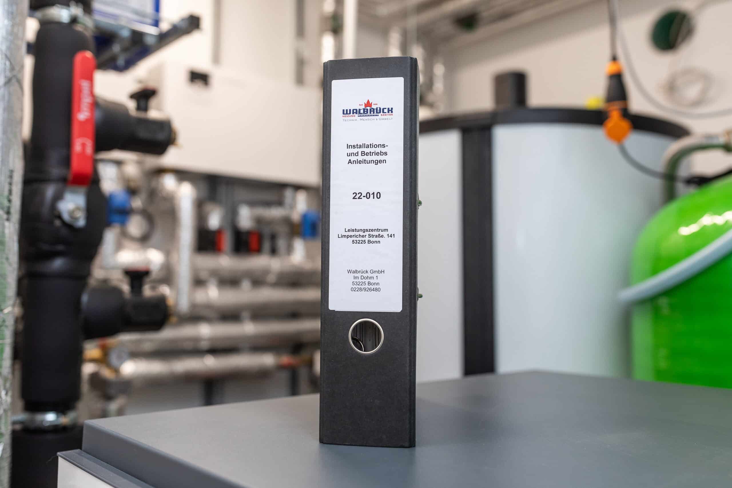 Walbrück-Wartungsordner vor einer Heizungsanlage im Technikraum