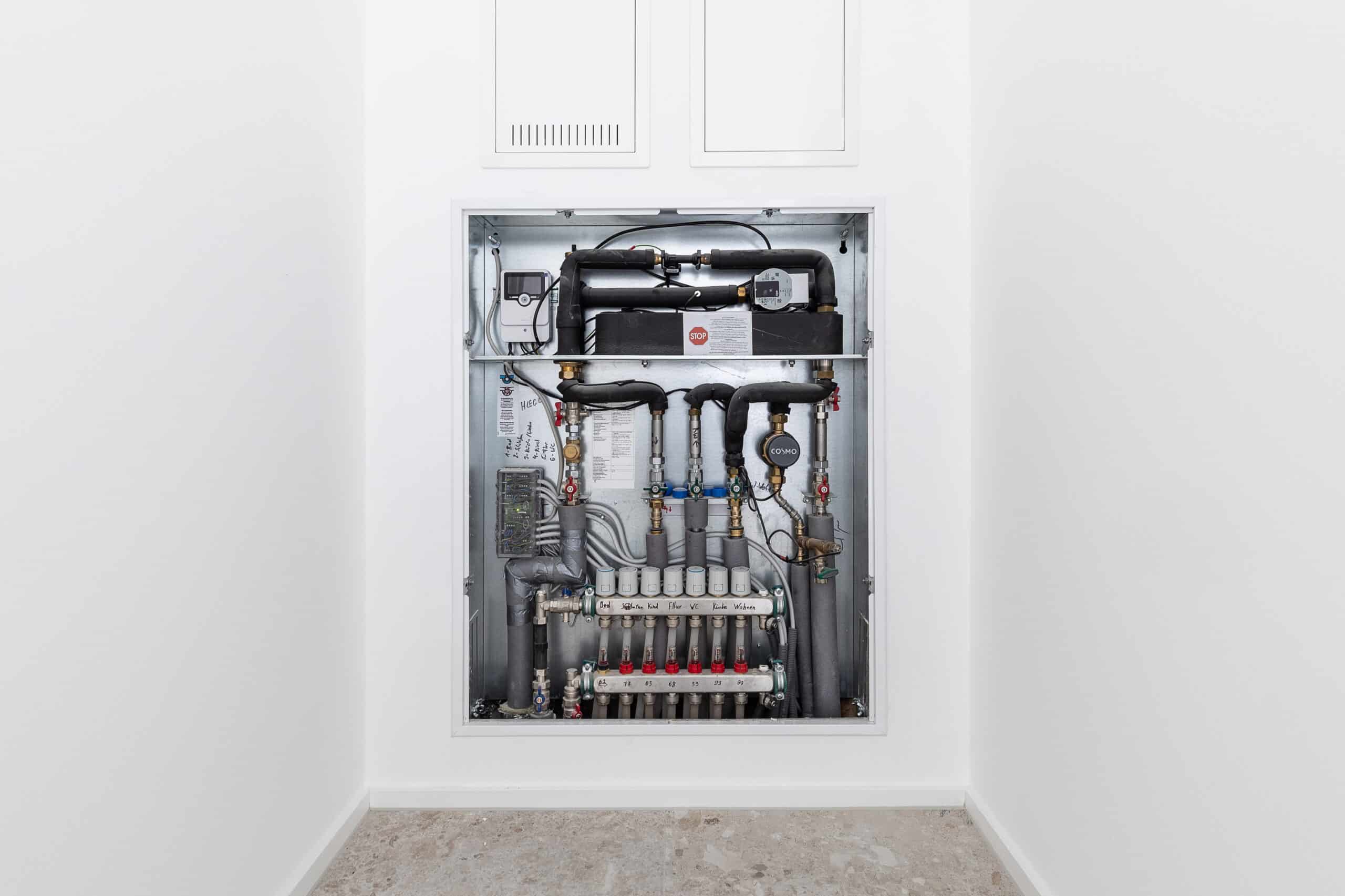 Geöffneter Wandeinbauschrank mit Wohnungsstation, Armaturen und Heizkreisverteiler