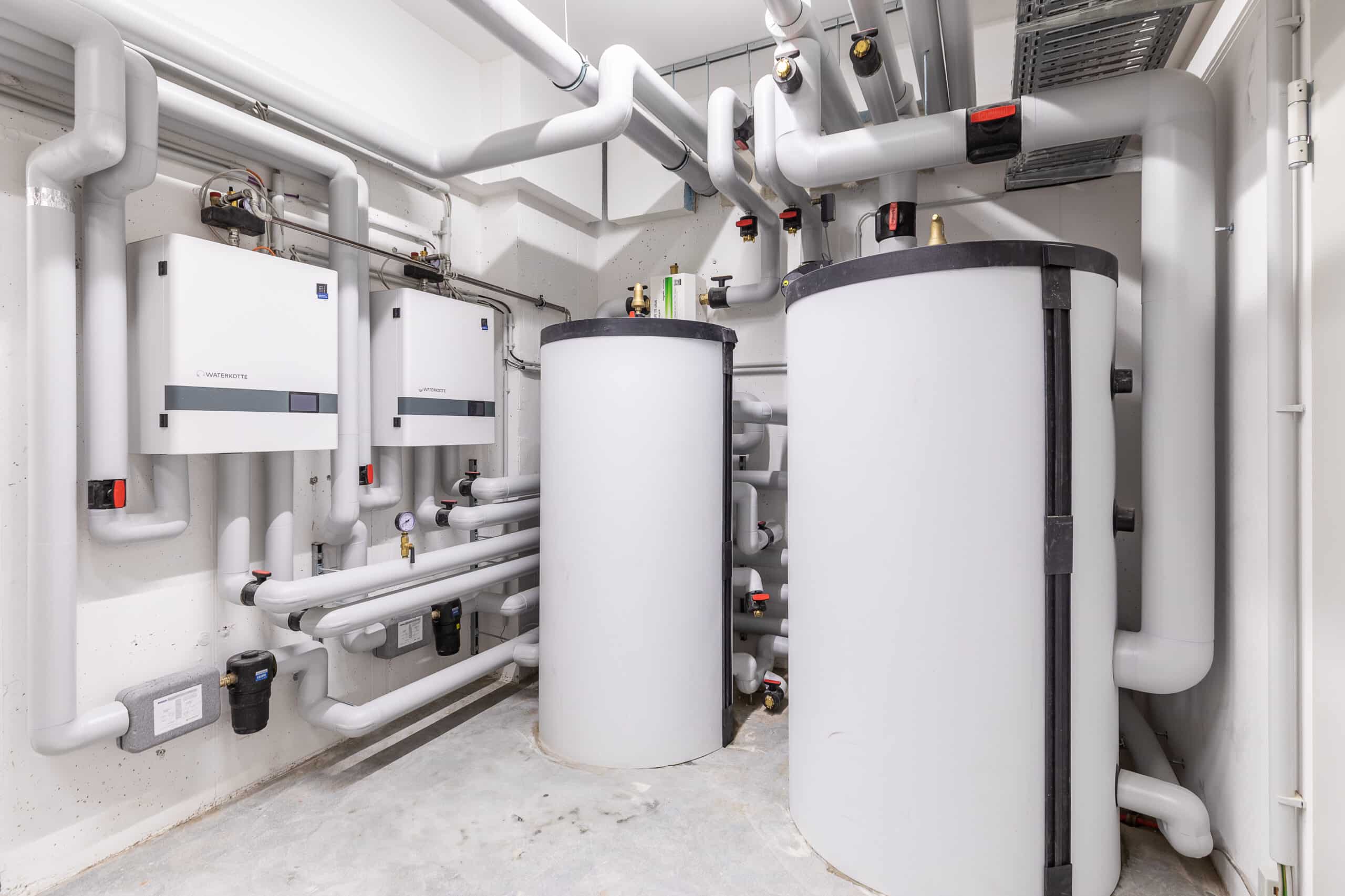 Heizungsanlage im Technikraum mit zwei Speichern, Heizgeräten und isolierten Rohrleitungen