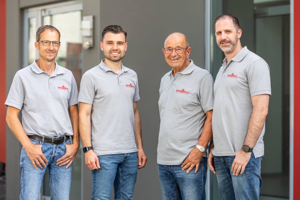 Vier Walbrück-Mitarbeiter in grauen Poloshirts vor dem Firmengebäude