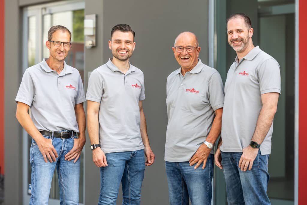 Vier Walbrück-Mitarbeiter in grauen Poloshirts vor dem Firmengebäude