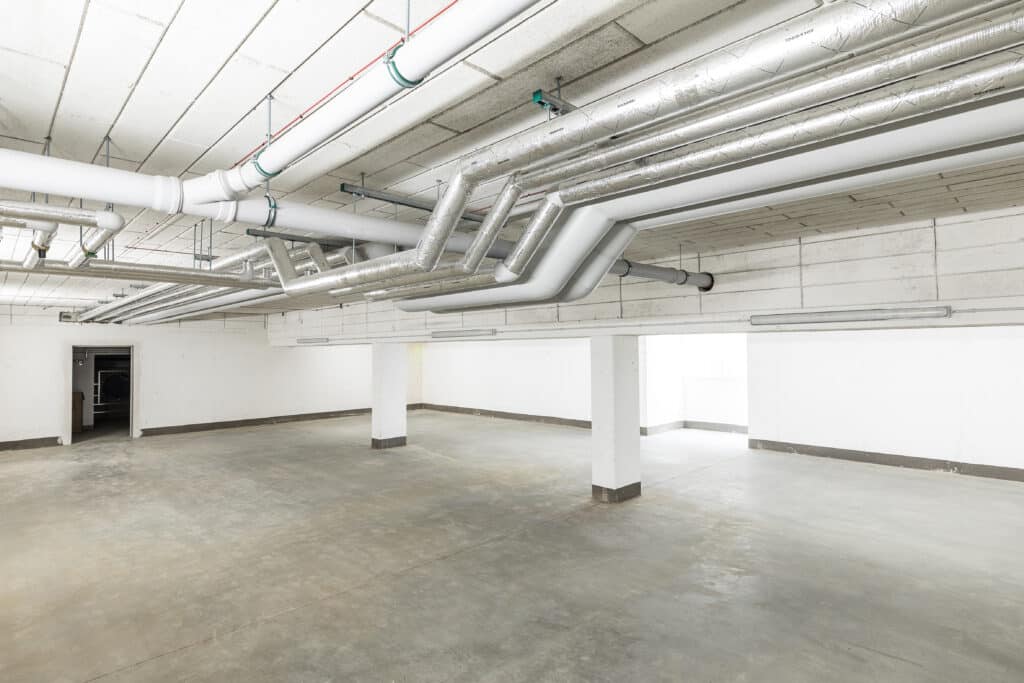 Rohrleitungen und Lüftungskanäle über den Stellflächen einer Tiefgarage