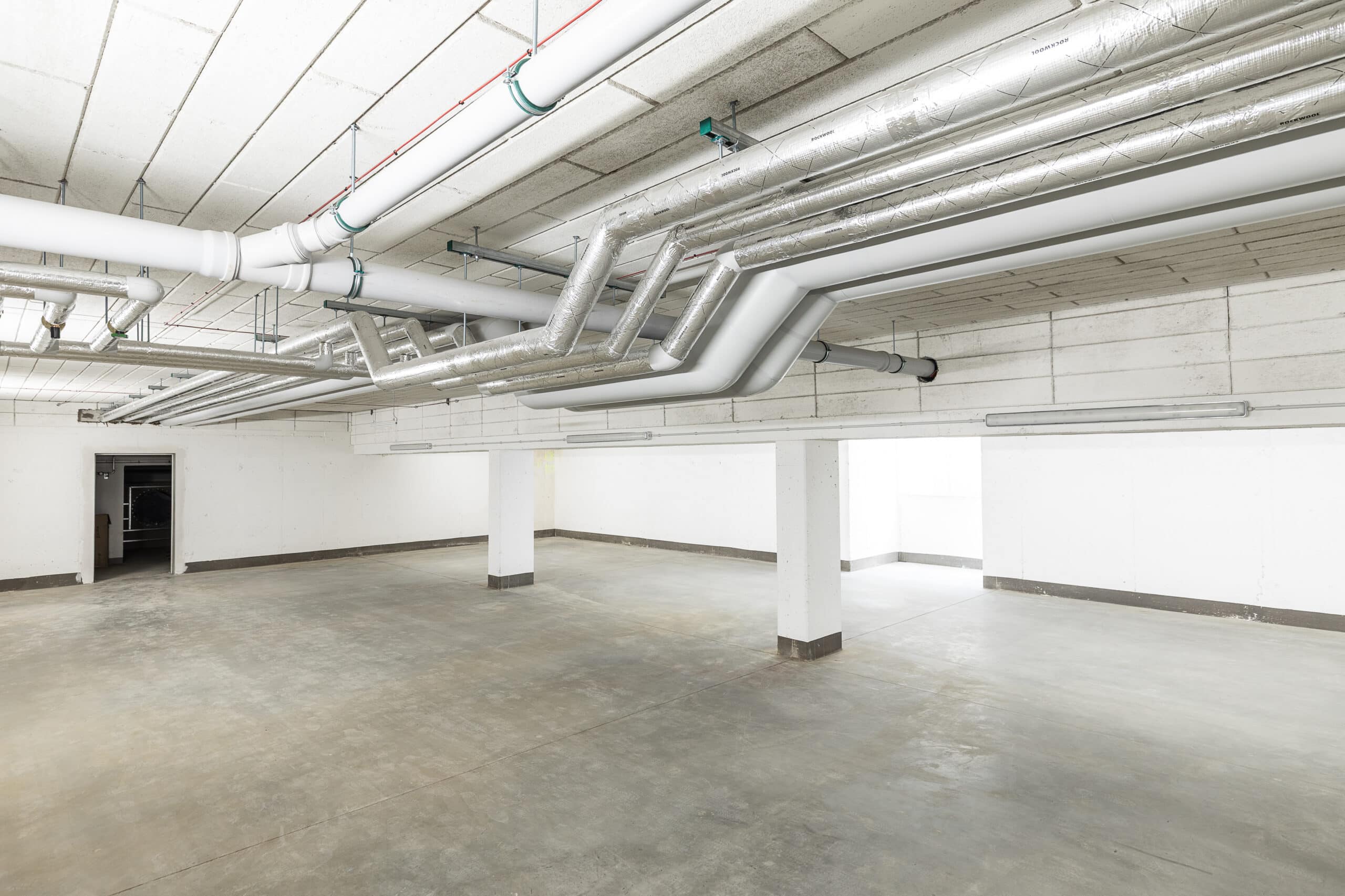 Rohrleitungen und Lüftungskanäle über den Stellflächen einer Tiefgarage
