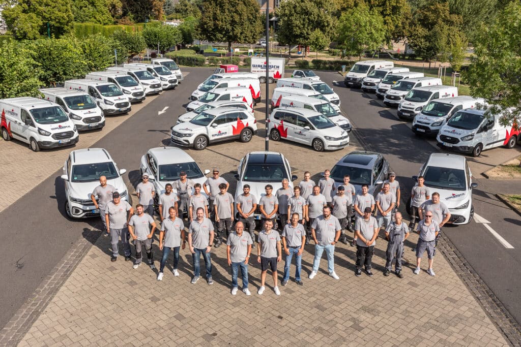 Walbrück-Team als Gruppenfoto vor dem in Reihen aufgestellten Fuhrpark