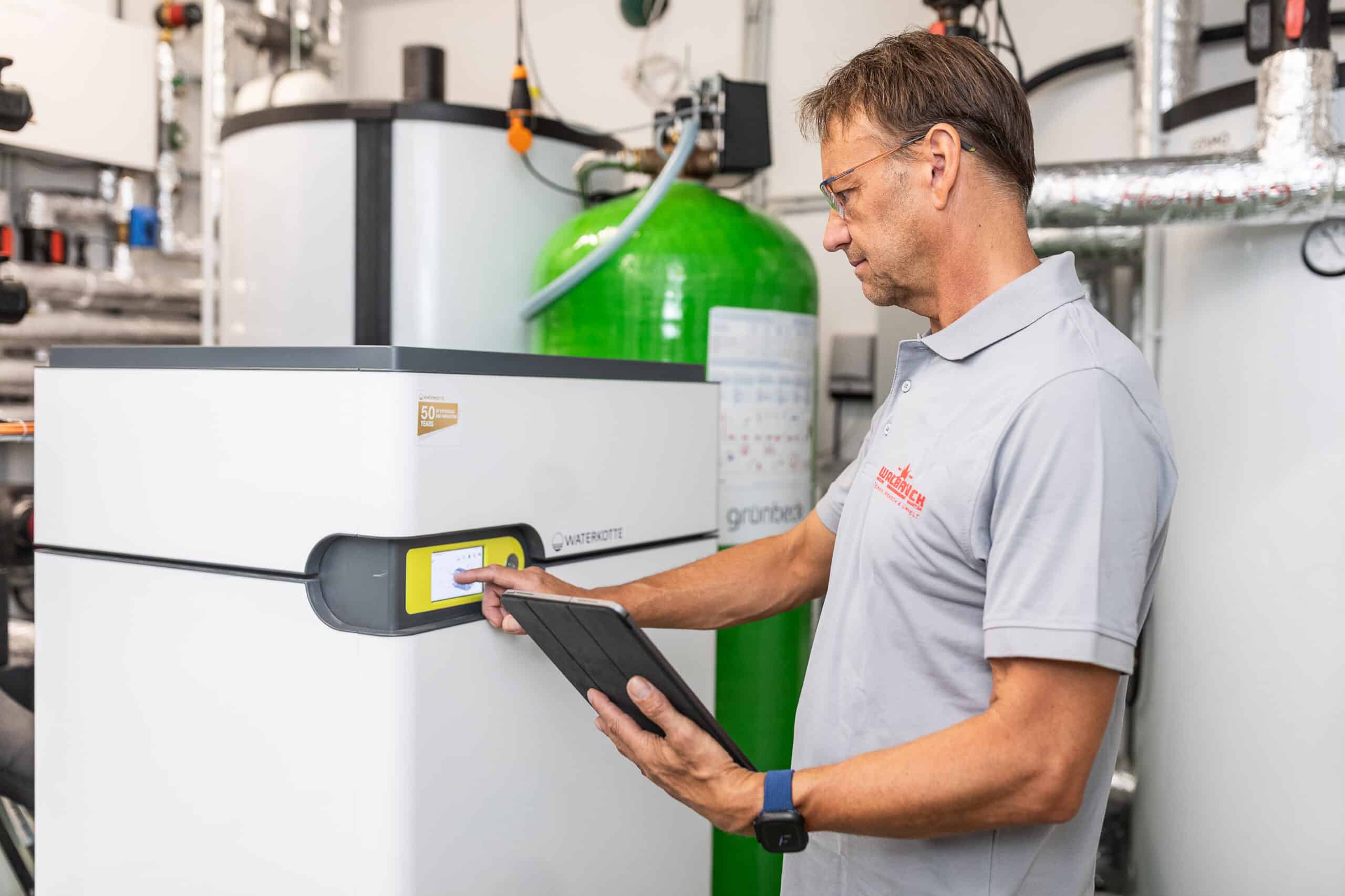 Walbrück-Techniker überprüft am Touchdisplay die Regelung einer Wärmepumpenanlage