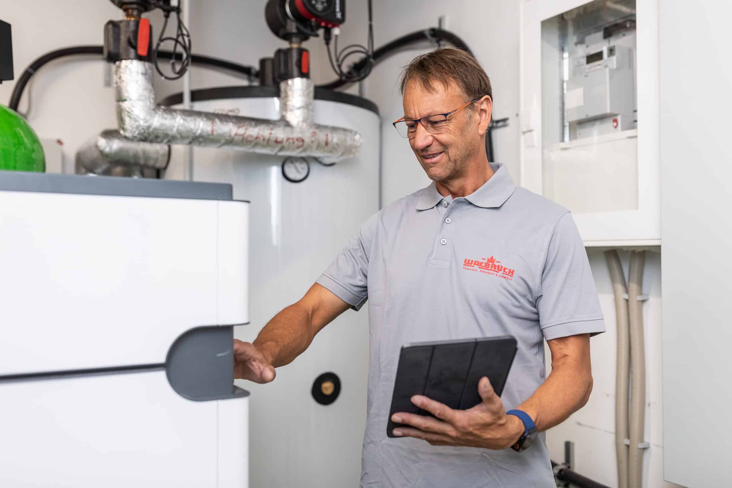 Walbrück-Techniker kontrolliert eine Wärmepumpen-Inneneinheit mit einem Tablet